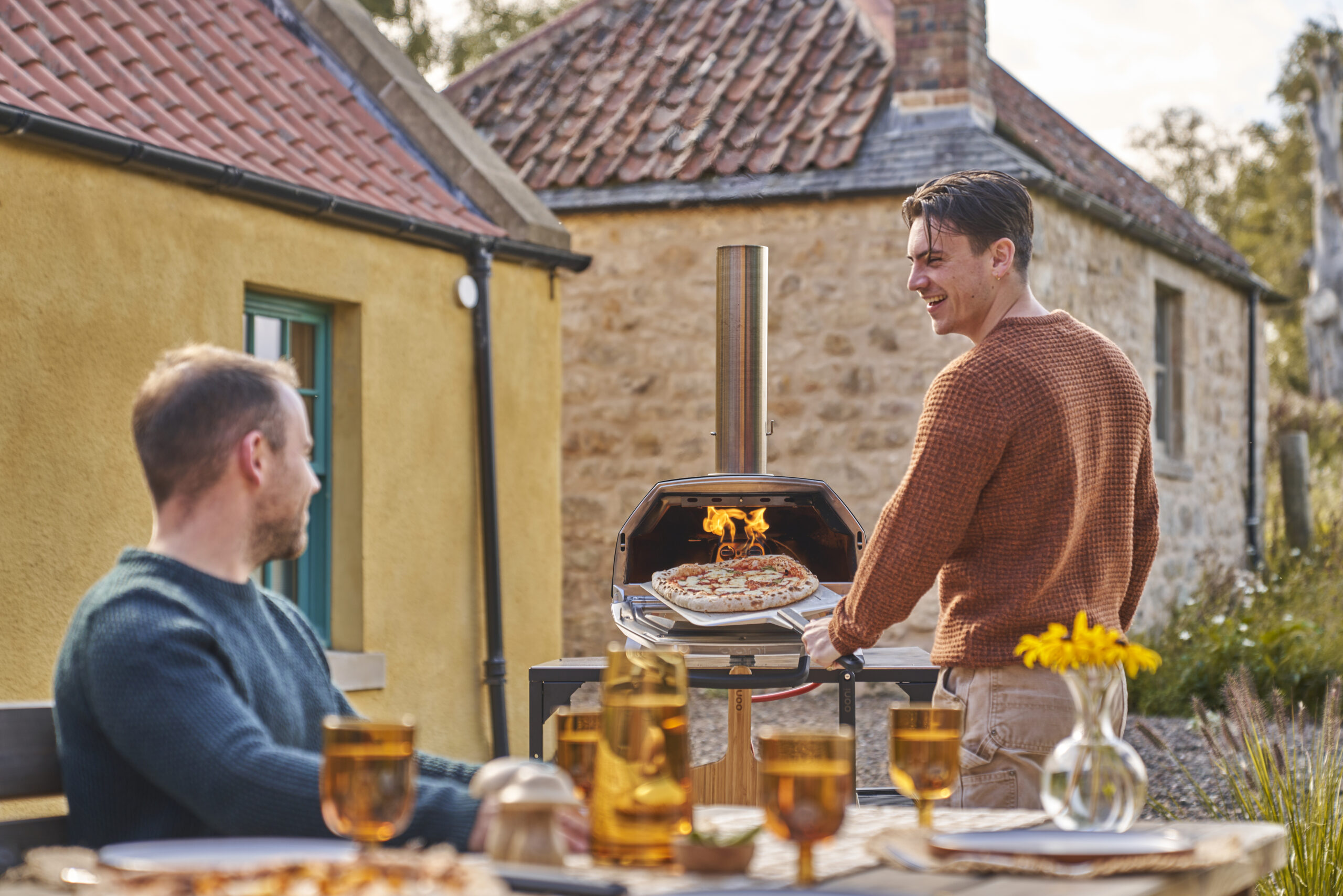 OONI Karu 16 Holz Gas Pizzaofen im Herbst – Freunde genießen frische Pizza aus dem Pizzaofen im Garten