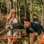 Freunde grillen Pizza mit dem Ooni Koda 12 Gas-Pizzaofen im Wald – tragbarer Outdoor-Pizzaofen für frische Steinofenpizza unterwegs