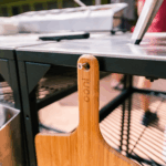 OONI Bambus-Pizzaschieber in Modultisch-Ablage – Holzpizzaschieber mit OONI-Logo als Tischzubehör