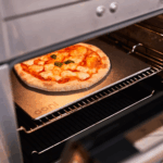 Fertig gebackene Margherita Pizza auf dem Ooni Pizzabackstahl im Haushaltsbackofen – goldbrauner knuspriger Boden dank Edelstahl-Backstahl mit Ooni-Logo