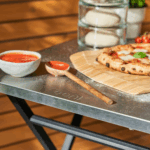 Fertige neapolitanische Pizza auf OONI Bambus-Pizzaschieber – Margherita mit Basilikum auf OONI Klapptisch