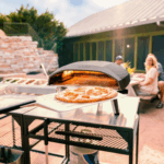 Ooni Koda 16 Pizzaofen mit frischer Pizza auf Terrasse im Sommer