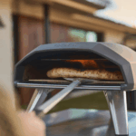 Ooni Koda 2 Pizzaofen in Schwarz beim Backen einer Pizza im Garten