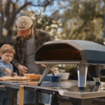 Vater und Sohn backen Pizza mit dem Ooni Koda 2 Pizzaofen in Dunkelblau im Garten