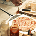 OONI Pizzaschieber L beim Pizza belegen – Tomatensauce auf Pizzateig verteilen für den OONI Pizzaofen