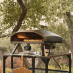 Ooni Koda 2 Pro Schwarz Gas-Pizzaofen im Garten mit Pizza auf Backstein und digitalem Thermometer