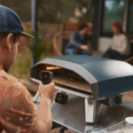 Person misst die Temperatur im Ooni Koda 2 Pro Dunkelblau Pizzaofen mit einem Infrarot-Thermometer