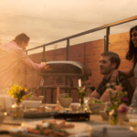 Freunde genießen Pizzaabend auf der Terrasse mit Ooni Koda 2 Max Gas Pizzaofen bei Sonnenuntergang