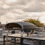 Ooni Koda 2 Max Gas Pizzaofen auf Dachterrasse mit Pizza und Stadtblick