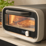 Ooni Volt 12 elektrischer Pizzaofen in Grau mit Pizza im Innenraum auf Küchentheke
