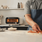 Ooni Volt 12 elektrischer Pizzaofen in Polareweiß in moderner Küche mit Pizzavorbereitung