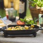 Ooni Gusseisen-Sizzler-Pfanne mit gegrilltem Gemüse auf gedecktem Tisch